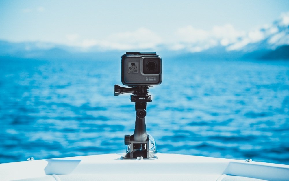 Camera mounted on a boat, capturing the serene blue water and distant mountains, emphasizing sound technology and innovation in outdoor settings.