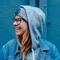 Smiling woman wearing glasses and a hoodie, representing the friendly and innovative team culture at Elite Aeolabs software development company.